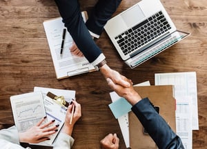 A sales meeting ending on an agreement and a handshake seen from above