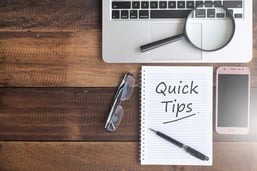 An overhead view of a laptop and notepad with the words 'quick tips' written on it